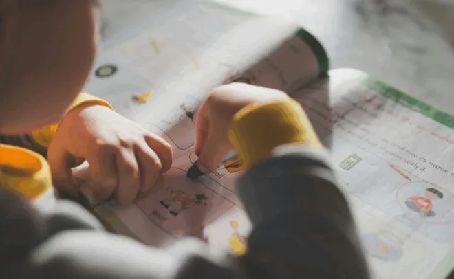 A young child completes a workbook activity.